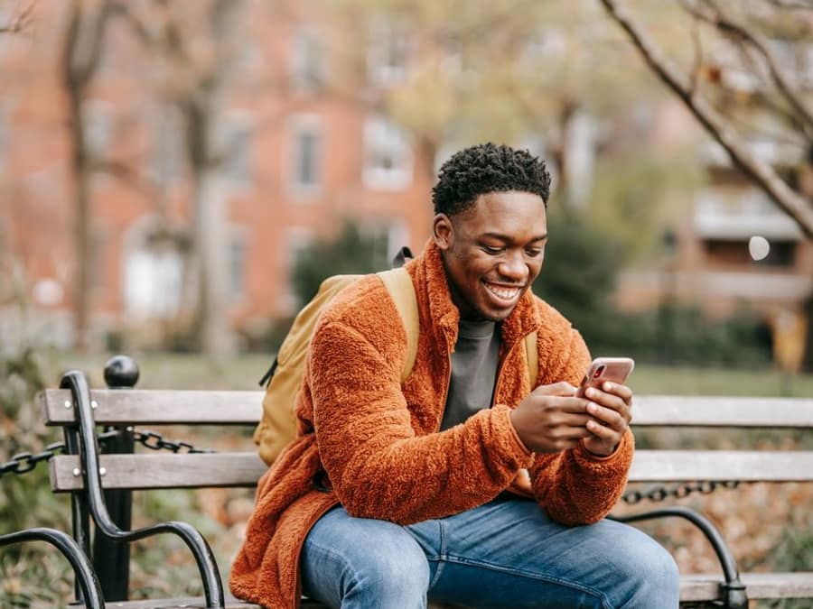 A young man smiling at his phone while chatting on WAYA
