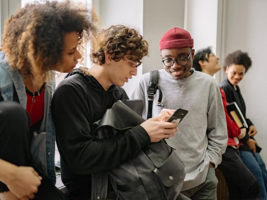Students laughing together around a phone on WAYA